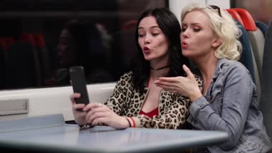 Young adult female friends travelling on a night train taking selfie