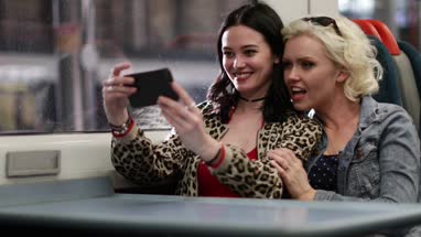 Young adult female friends travelling on train taking selfie