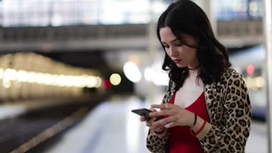 Young adult female on station platform using smartphone