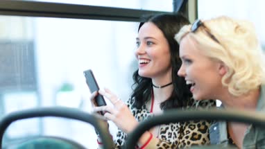Female friends travelling through London on a bus