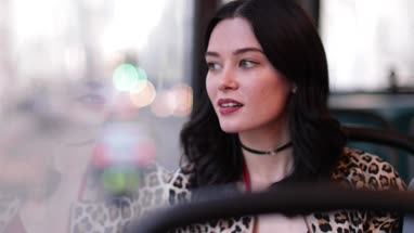 Young adult female travelling on bus looking out of window