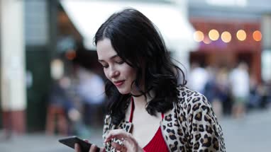 Young adult female using smartphone on street