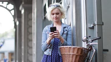 Young adult female with bicycle using smartphone