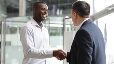Businessmen shaking hands in a corporate office