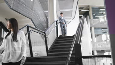 Businessman and businesswoman walking down stairs in an office