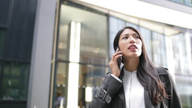 Businesswoman on smartphone looking around