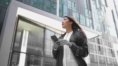 Businesswoman using smartphone walking in city