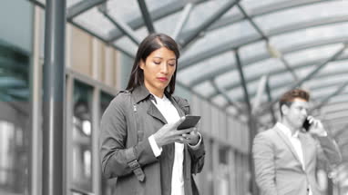 Businesswoman waiting for train on platform with smartphone in hand