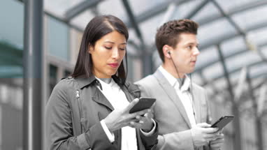 Businesswoman waiting for train on platform with smartphone in hand