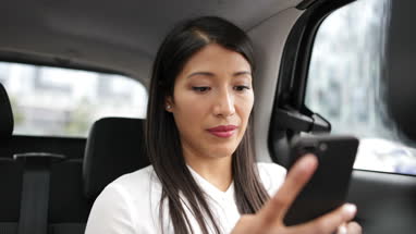Businesswoman in taxi cab using smartphone