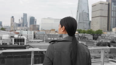 Businesswoman looking out at London city skyline