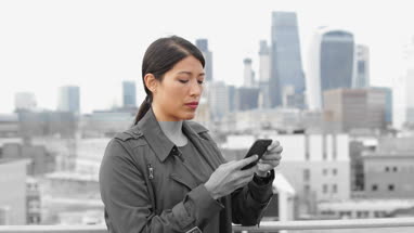 Businesswoman using smartphone with London city skyline