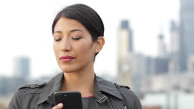 Businesswoman using smartphone with London city skyline