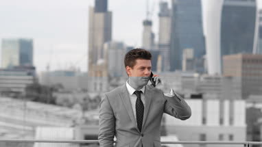 Businessman using smartphone looking out at London city skyline