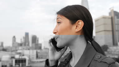 Businesswoman using smartphone looking out at London city skyline