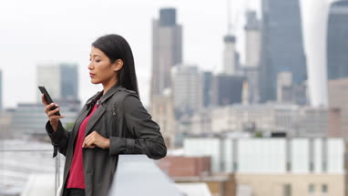 Businesswoman using smartphone with London city skyline