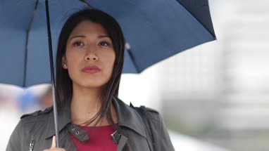 Businesswoman in city holding umbrella in bad weather