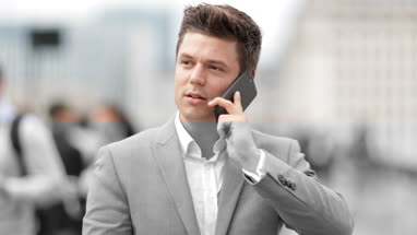 Businessman talking on smartphone on crowded street
