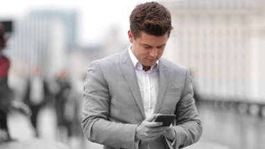 Businessman using smartphone on crowded street
