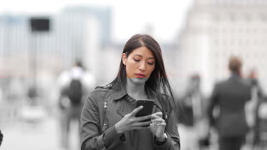 Businesswoman using smartphone on crowded street