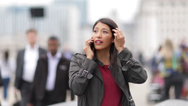 Businesswoman talking on smartphone on crowded street