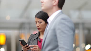 Commuter looking at train times at station holding smartphone