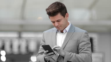 Commuter looking at train times at station holding smartphone
