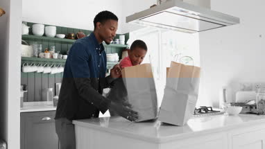 Boy helping Father unpack groceries