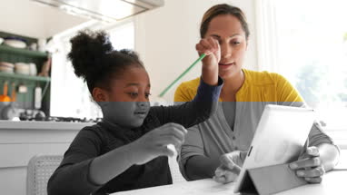 Mother teaching Daughter with the help of digital tablet
