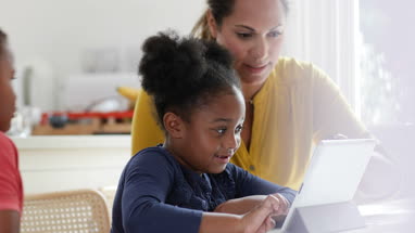 Mother teaching children how to use digital tablet