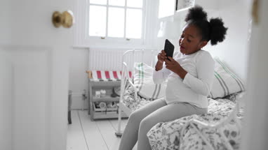 Girl playing with smartphone in her bedroom