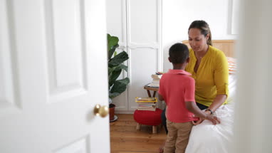 Mother helping son dress in the morning