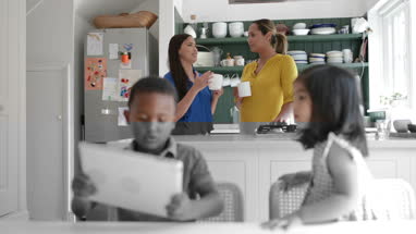 Mums talking whilst kids play with digital tablet