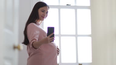 Pregnant woman taking selfie with smartphone
