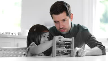 Girl using abacus to count with Father
