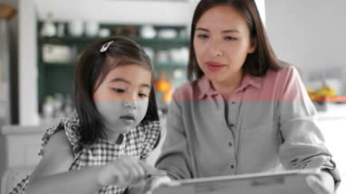Mother teaching Daughter how to use digital tablet