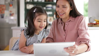Mother teaching Daughter how to use digital tablet