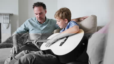 Father teaching son guitar chords