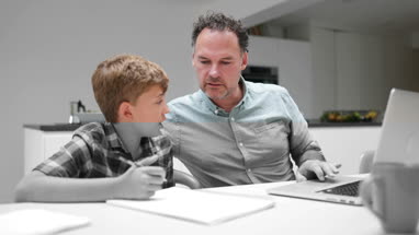 Father helping son with homework using a laptop