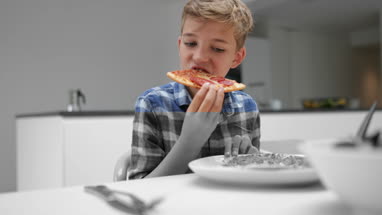Boy taking a bite out of a slice of pizza