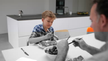 Father giving his Son some salad with a meal