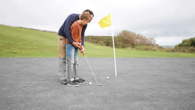 Father teaching son how to play golf