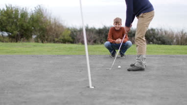 Son watching Father play golf