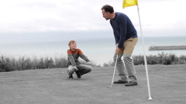 Son watching Father play golf