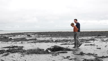 Father and Son walking on natural beach learning about environment