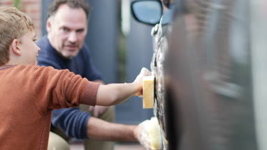 Son helping Father wash car