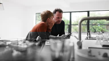 Father and Son in kitchen looking at smartphone