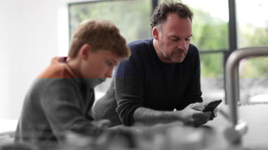 Father and Son in kitchen looking at smartphone