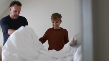 Father teaching Son to make a bed