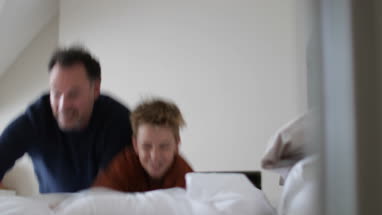 Father and Son jumping on newly made bed
